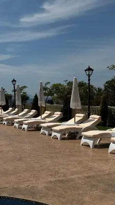 a row of white lounge chairs with umbrellas at Santa Maria Luxury Suits in Ravda