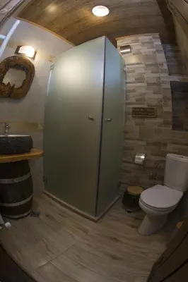 a bathroom with a toilet and a glass shower stall at Chateau Erkech Triple Room in Kozichino