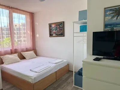 a small room with a bed and a television at Оазис in Ravda