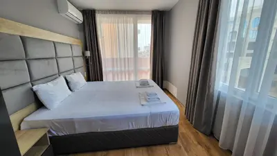 a bedroom with a bed and a large window at Marina Bay Apartmant in Pomorie
