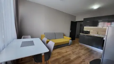 a small room with a table and a yellow couch at Marina Bay Apartmant in Pomorie