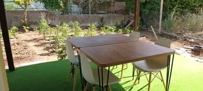 a wooden table and chairs in a garden at Стаи за гости Пансионът на Роуз Вълшебната ми Кръстница in Chernomorets