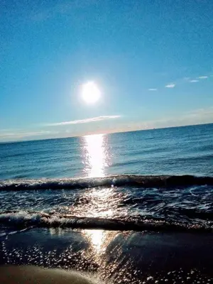 a beach with the sun reflecting on the water at Stela in Burgas City