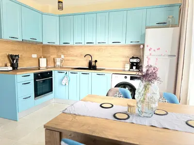 a kitchen with blue cabinets and a wooden table at Boho and More in Sozopol