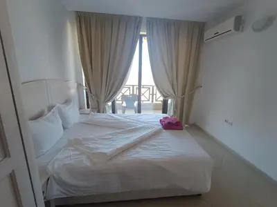 a white bed in a room with a window at Oasis Beach 2 bedroom apartment in Lozenets