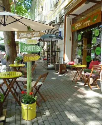 an outdoor cafe with tables and chairs and an umbrella at Cozy 1-bedroom apartment 5 min from the beach in Varna City