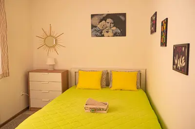 a bedroom with a green bed with yellow pillows at Cozy 1-bedroom apartment 5 min from the beach in Varna City