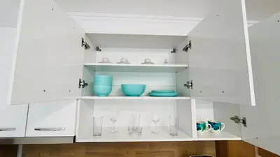 a white cabinet with glasses and bowls on it at KAYA Atelie 1 Sunny Beach in Sunny Beach