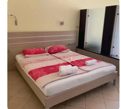 a large bed with red sheets and pillows on it at Central Beach Apartament in Sunny Beach