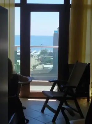 a person sitting in a chair in front of a window at Central Beach Apartament in Sunny Beach
