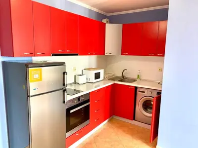 a kitchen with red cabinets and a washer and dryer at DELFIN Penthouse amazing view in Sveti Vlas