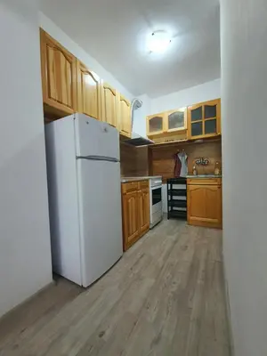 a kitchen with a white refrigerator and wooden cabinets at Apartament Lazur 13 in Burgas City