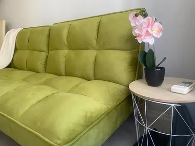 a green couch sitting next to a table with flowers at JOY Studio in Ravda