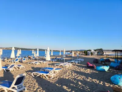 a beach with chairs and umbrellas and the water at Студио 310 на първа линия in Chernomorets