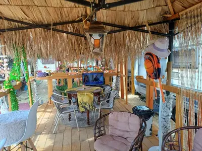a patio with a table and chairs and a television at Къмпинг Европа Юг in Burgas City