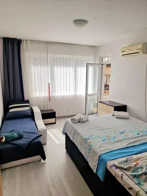 a bedroom with two beds and a chair in it at Апартамент Бижу М in Pomorie