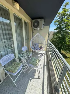 a balcony with chairs and a table and a bird cage at Прекрасно студио in Sunny Beach