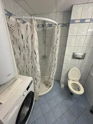 a bathroom with a shower and a washing machine at Прекрасно студио in Sunny Beach