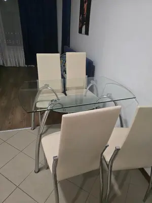 a glass table with four white chairs around it at POMORIE Blue Bay in Pomorie
