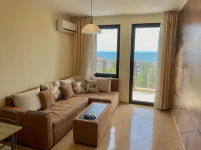 a living room with a couch and a large window at DELFIN Sea view in Sveti Vlas