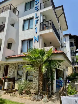 a building with a palm tree in front of it at DELFIN Sea view in Sveti Vlas