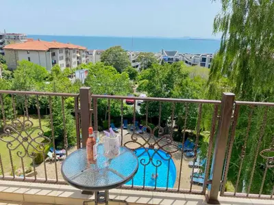 a table on a balcony with a view of a yard at DELFIN Sea view in Sveti Vlas