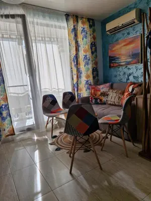 a living room with a couch and a table and chairs at Студио в Затворен Комплекс Blue in Sozopol