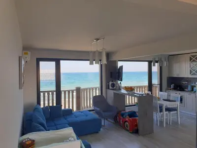 a living room with a blue couch and a view of the ocean at Solar Rise apartment in Pomorie