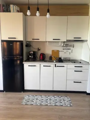 a kitchen with white cabinets and a black refrigerator at Marina Cape Sky View Lux Apartment in Aheloy in Aheloy