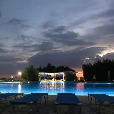 a large swimming pool with blue tables and chairs at night at Marina Cape Sky View Lux Apartment in Aheloy in Aheloy