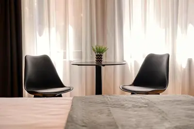 two chairs and a table in a room with a bed at Smart Rooms in Varna City