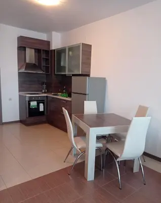 a kitchen with a wooden table and white chairs at Студио Море in Chernomorets