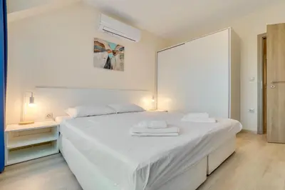 a white bedroom with a white bed and a window at AT apartment - Sea View in Varna City