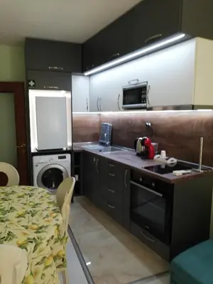 a kitchen with black cabinets and a table and a stove at SPS Apartment in Varna City
