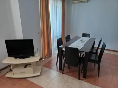 a dining room with a table and a television at Апартамент Плаж Червенка in Chernomorets