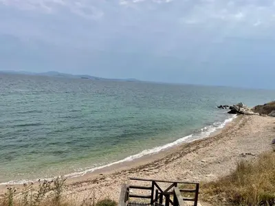 a bench sitting on a beach near the water at Majestic Villas Pomorie Park in Sarafovo