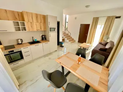 a kitchen and living room with a table and chairs at Majestic Villas Pomorie Park in Sarafovo