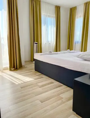 a bedroom with a large bed and wooden floors at Majestic Villas Pomorie Park in Sarafovo