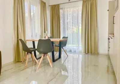 a dining room with a wooden table and chairs at Majestic Villas Pomorie Park in Sarafovo