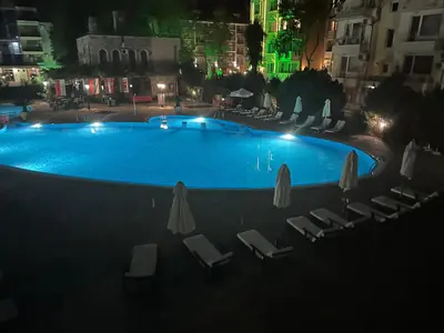a swimming pool at night with chairs and umbrellas at Kalia A5 Sunny Beach in Sunny Beach