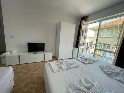 a bedroom with a white bed and a television at Apartments Lozenets in Lozenets
