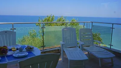 a table and chairs on a balcony with the ocean at Апартаменти Бяла Бийч - Apartments Byala Beach in Byala