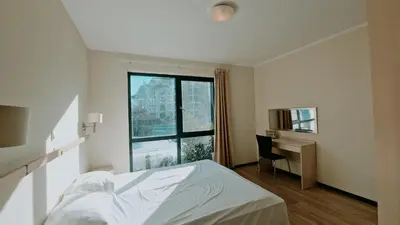 a bedroom with a bed and a desk and a window at Апартаменти Бяла Бийч - Apartments Byala Beach in Byala