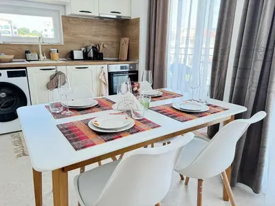 a dining room table with white chairs and a kitchen at Saltwater Escape in Sozopol in Sozopol
