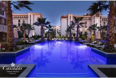 a large pool with palm trees in front of a building at Cascadas pool view luxury apartment Sunny beach in Sunny Beach