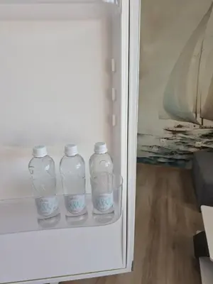 three glass bottles are sitting in a refrigerator at Апартамент 