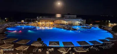 a large pool with blue water at night at MIDIA Family Resort - studio s výhledem na moře in Aheloy