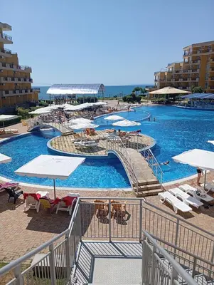 a large swimming pool with white umbrellas and chairs at MIDIA Family Resort - studio s výhledem na moře in Aheloy