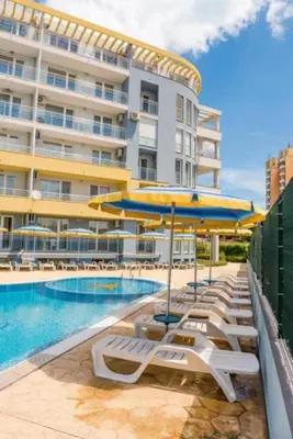 a pool with chairs and umbrellas next to a building at Sea Apartament Kristal Beach,Nessebar in Nesebar