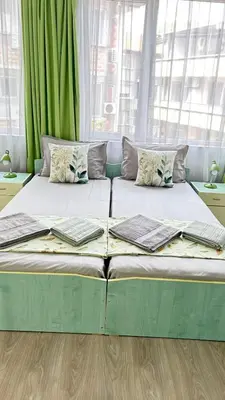 a large bed in a room with green curtains at Guest House Dani in Pomorie